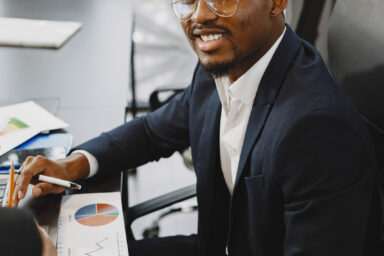 African man in a black suit. International partners. People sitting at the table with laptop.